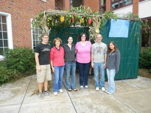 stidents and faculty members in front of sukkah tent