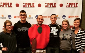 Conference attendees pose in front of conference logo, Hoynak dressed as an apple.
